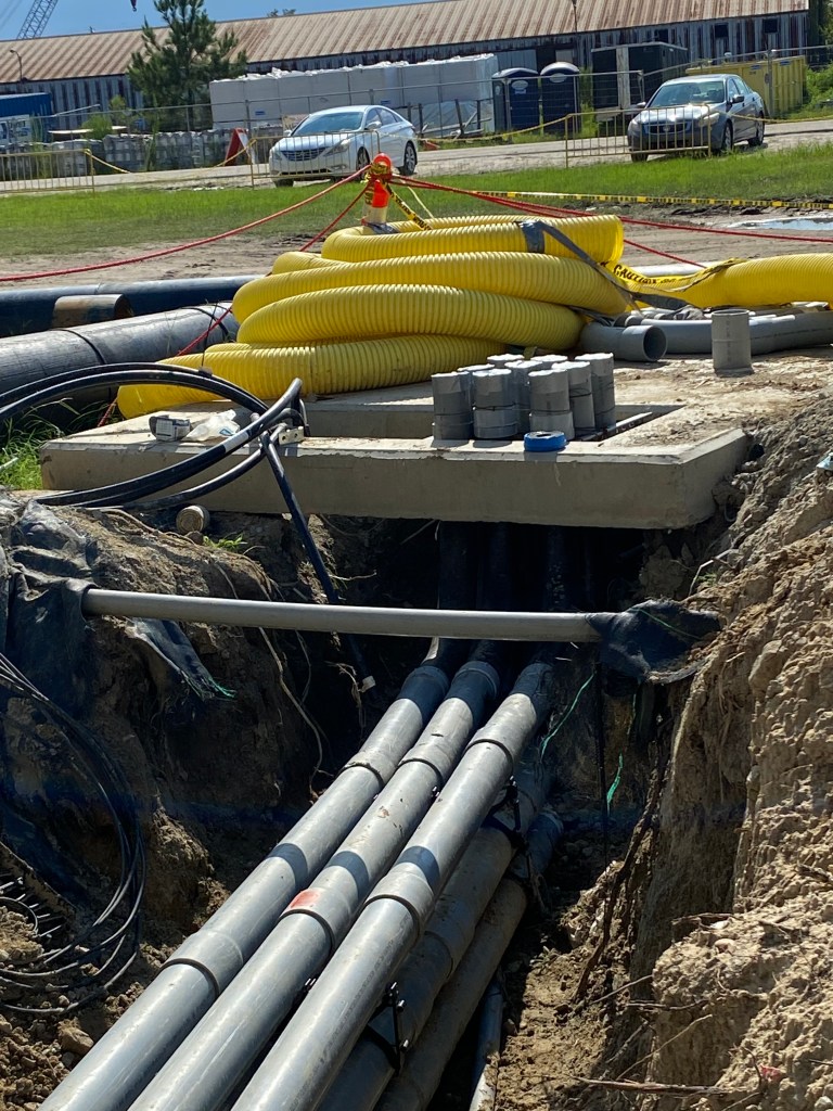 A construction site with yellow coiled hose, exposed pipes, and utility lines. ## Image Summary Construction site featurin...